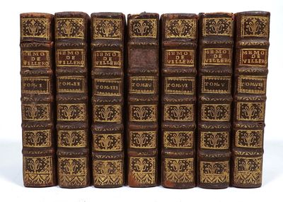 several old books are lined up in a row on a white surface