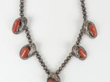 a necklace with red beads and silver beads on a white background