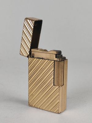 a gold lighter with a black lid sitting on top of a white surface