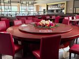 de nombreuses chaises rouges disposées autour d'une table ronde dans un restaurant