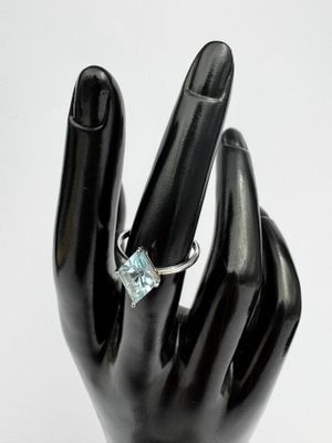 une main sur laquelle est passée une bague sertie d'une pierre bleue