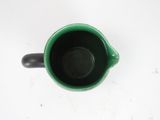 a green cup with a black handle on a white table