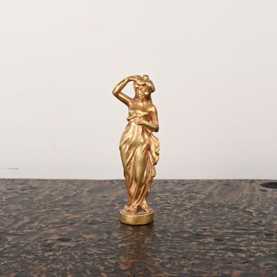 une statue en or représentant une femme, posée sur une table en marbre
