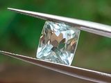 quelqu'un tient une pince dans laquelle est sertie un diamant bleu clair