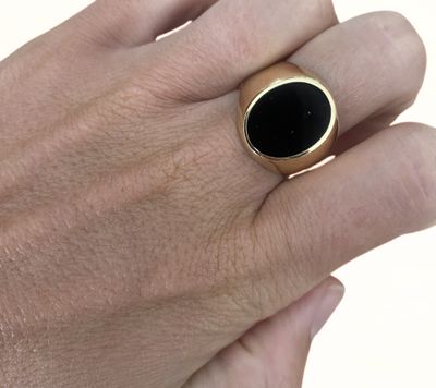 la main d'un homme tenant une bague sertie d'une pierre noire