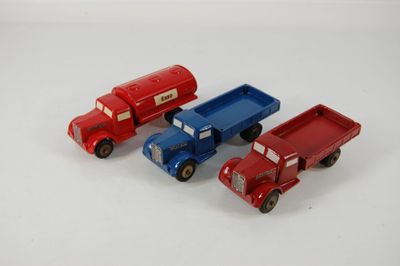 quatre camions miniatures posés les uns à côté des autres sur une surface blanche