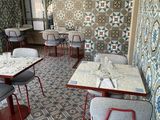 many tables and chairs in a restaurant with a tiled wall