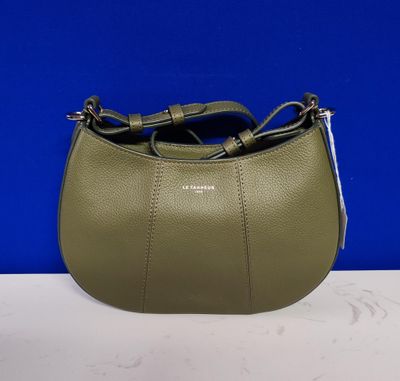 un sac à main vert muni d'une poignée en métal, posé sur une table blanche