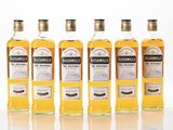 four bottles of whisky are lined up in a row on a white surface