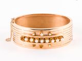 Le bracelet est en or, orné de perles et d'une chaîne qui l'entoure.