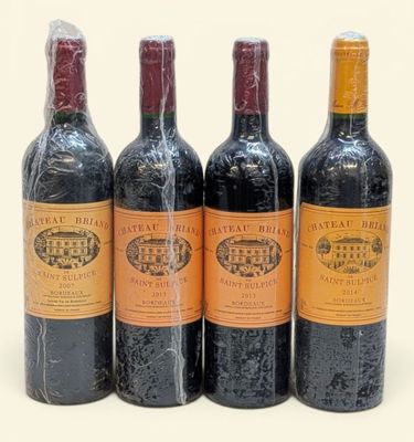 trois bouteilles de vin rouge sont alignées sur une surface blanche