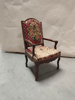 une vieille chaise dont le dossier et l'assise sont recouverts d'un tissu à motifs floraux