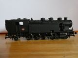 un petit train miniature posé sur une table en bois, avec un mur blanc en arrière-plan