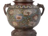 un grand vase en métal surmonté d'un chien