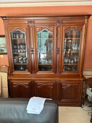 un fauteuil en cuir noir placé devant un vaisselier en bois