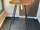 un tabouret avec une assise en bois, placé devant une fenêtre
