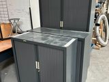 une armoire noire à deux portes, avec un vélo en arrière-plan
