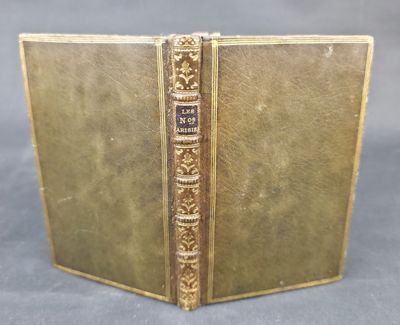 an old book with a gold cover sitting on top of a table