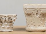 two white vases sitting on a table next to each other