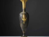 un vase noir et doré posé sur une table blanche
