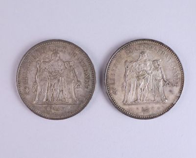two silver coins sitting side by side on a white surface