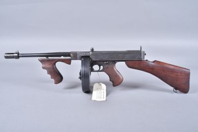 un gros plan d'un pistolet posé sur une surface blanche, sur lequel est accrochée une étiquette