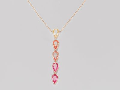 a gold necklace with a pink and white stone pendant on it