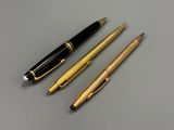 two pens and a ballpoint pen sitting on top of a table