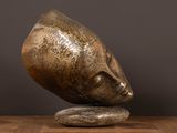 une sculpture en bronze représentant le visage d'une femme sur un rocher