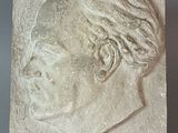 plaster portrait of a woman ' s head on a plaque