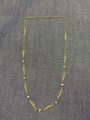 un collier en or orné de perles sur fond gris