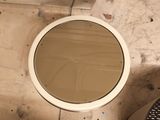 a toilet with a round mirror on the top of it