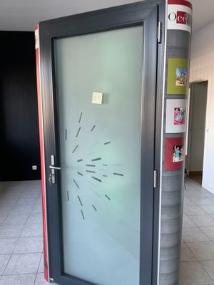 une porte vitrée sur laquelle est accrochée une horloge, dans une pièce