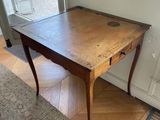a wooden table with a drawer on it in the corner of a room