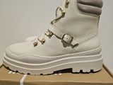 white leather boots with gold buckles on top of a cardboard box