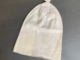 white baby hat with a flower on top of it on a gray surface