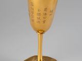 a gold goblet with chinese writing on it sitting on a table