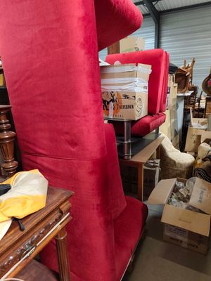 a red chair in the middle of a room filled with boxes