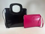 two black and pink purses sitting next to each other on a table