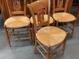 Quatre chaises en bois sont alignées en rangée dans une pièce.
