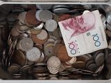 un récipient métallique rempli de pièces et de billets posé sur une table