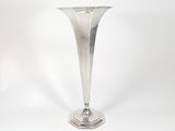 a silver vase that is sitting on a white surface