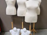 Trois mannequins blancs sont exposés devant un mur
