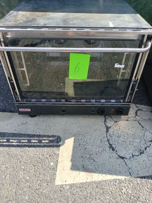 un petit four posé sur le trottoir, avec un autocollant vert dessus
