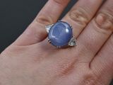 woman ' s hand holding a ring with a blue stone on it