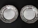 two silver plated dishes on a black surface