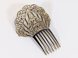 a silver comb with a design on it on a white surface