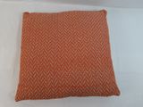a close up of an orange pillow on a white surface