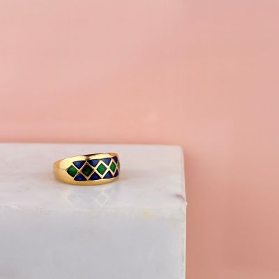 une bague en or sertie de diamants noirs et verts sur fond rose