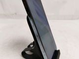 the back of a black cell phone on a stand on a white surface